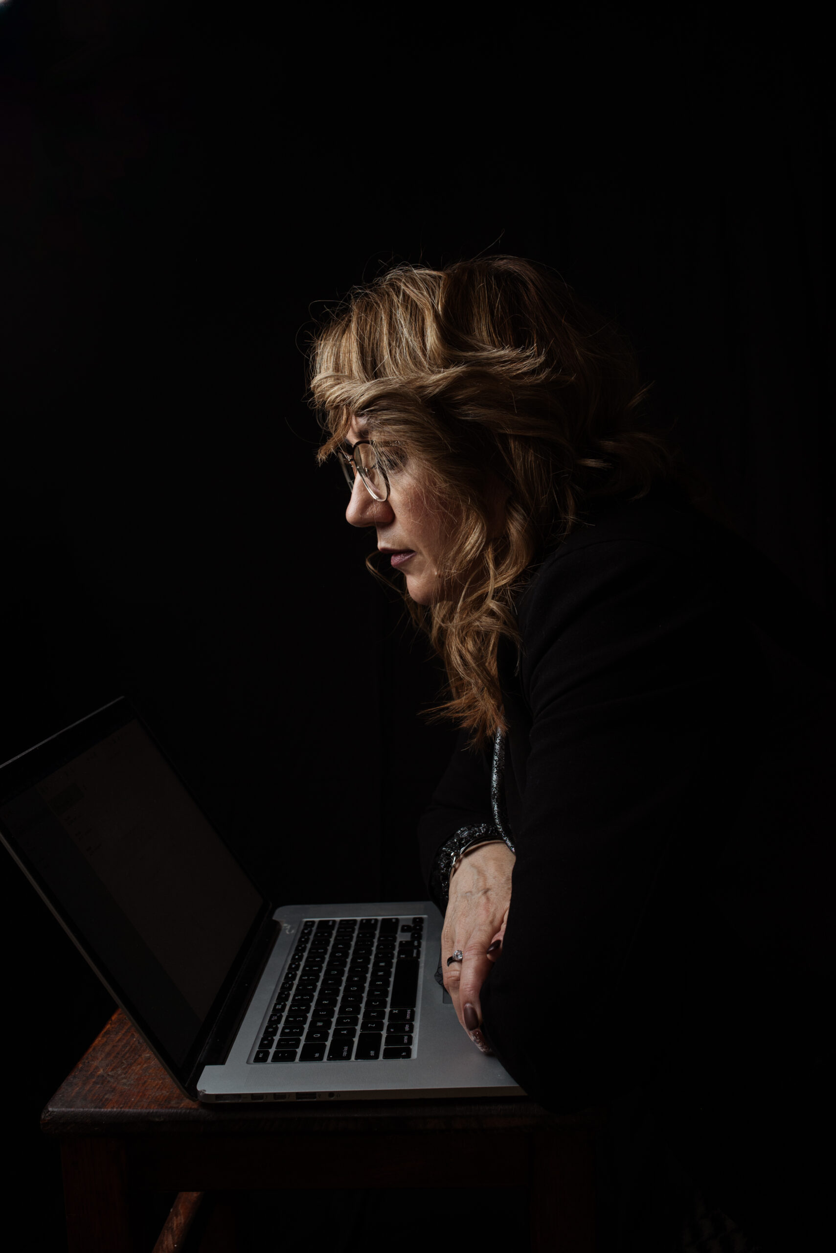 Personne concentrée devant un ordinateur portable dans un bureau sombre